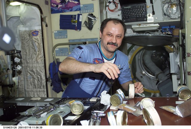 STS104-E-5126 (16 July 2001) --- Cosmonaut Yury V. Usachev, Expedition Two commander, appears surrounded by food in the Zvezda service module aboard the International Space Station (ISS). Representing Rosaviakosmos, Usachev, commander, along with two astronauts, are hosting the STS-104 crew of astronauts on the International Space Station (ISS). The image was recorded with a digital still camera.