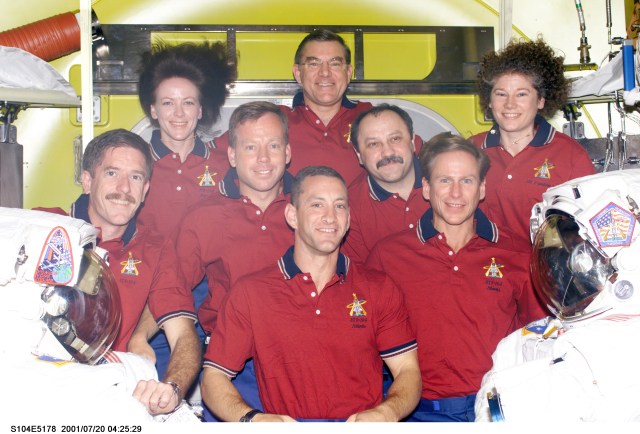 Seven astronauts and a cosmonaut representing Rosaviakosmos take a break in joint activities involving the Expedition Two and STS-104 crews to pose for an inflight portrait in the newly delivered Quest Airlock on the International Space Station (ISS). Charles O. Hobaugh is in front. On the second row are, from the left, James F. Reilly, Steven W. Lindsey, Yury V. Usachev and Michael L. Gernhardt. In the rear are astronauts Janet L. Kavandi, James S. Voss and Susan J. Helms. Usachev, commander; along with Voss and Helms, both flight engineers, comprise the Expedition Two crew. Lindsey is STS-104 commander, with Hobaugh serving as pilot. Kavandi, STS-104 flight engineer, is joined by Gernhardt and Reilly as mission specialists on the mission. This image was recorded with a digital still camera.