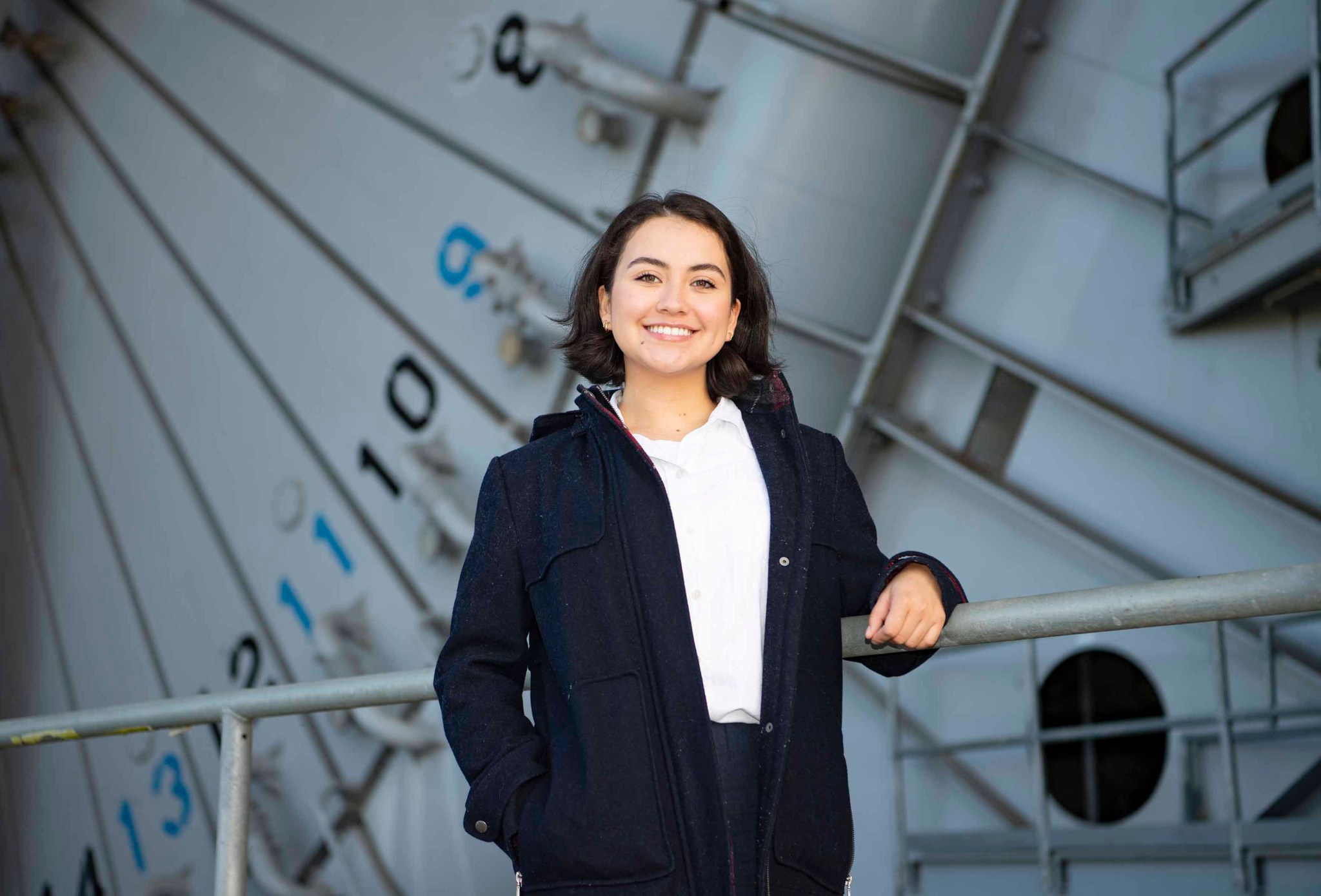 A young woman stands in front of the near the Fred Haise Test Stand