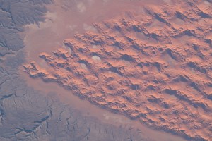 Wind shapes a prominent network of sand dunes in part of the Sahara Desert as the International Space Station orbited roughly 260 miles above Algeria. Each year, an estimated 100 million tons of dust is picked up by winds in the area.