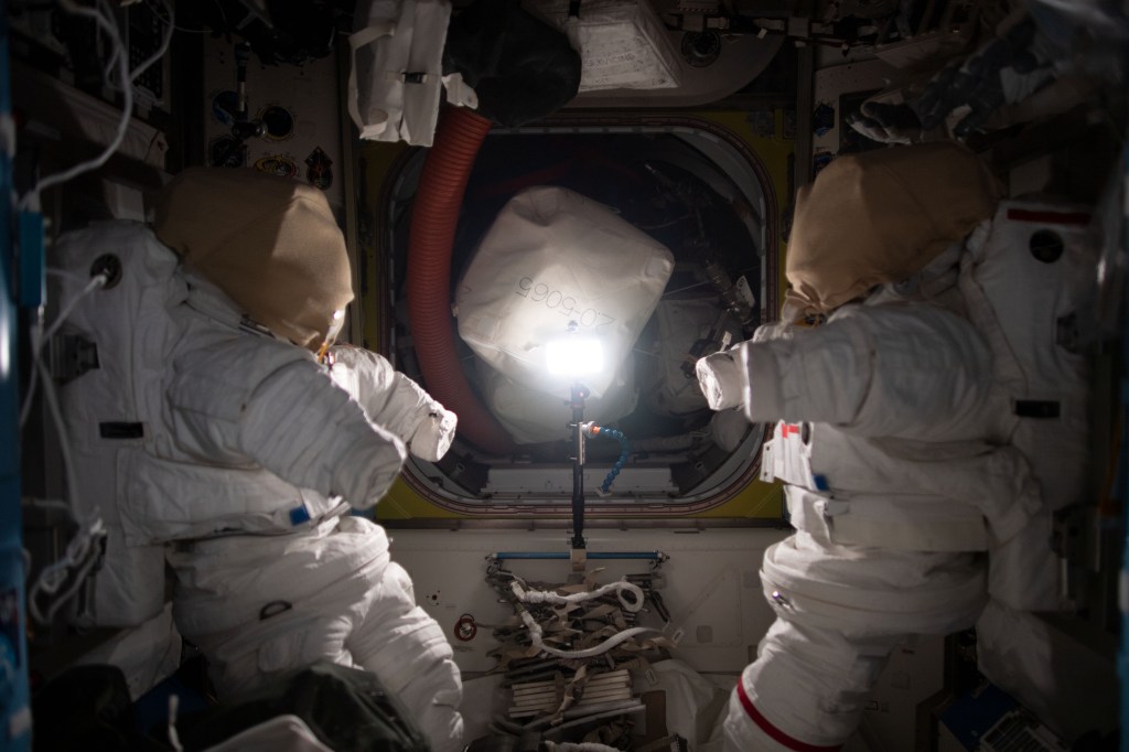A pair of Extravehicular Mobility Units (EMUs), or spacesuits, is pictured inside the International Space Station's Quest airlock where spacewalks are staged by astronauts wearing the EMUs.