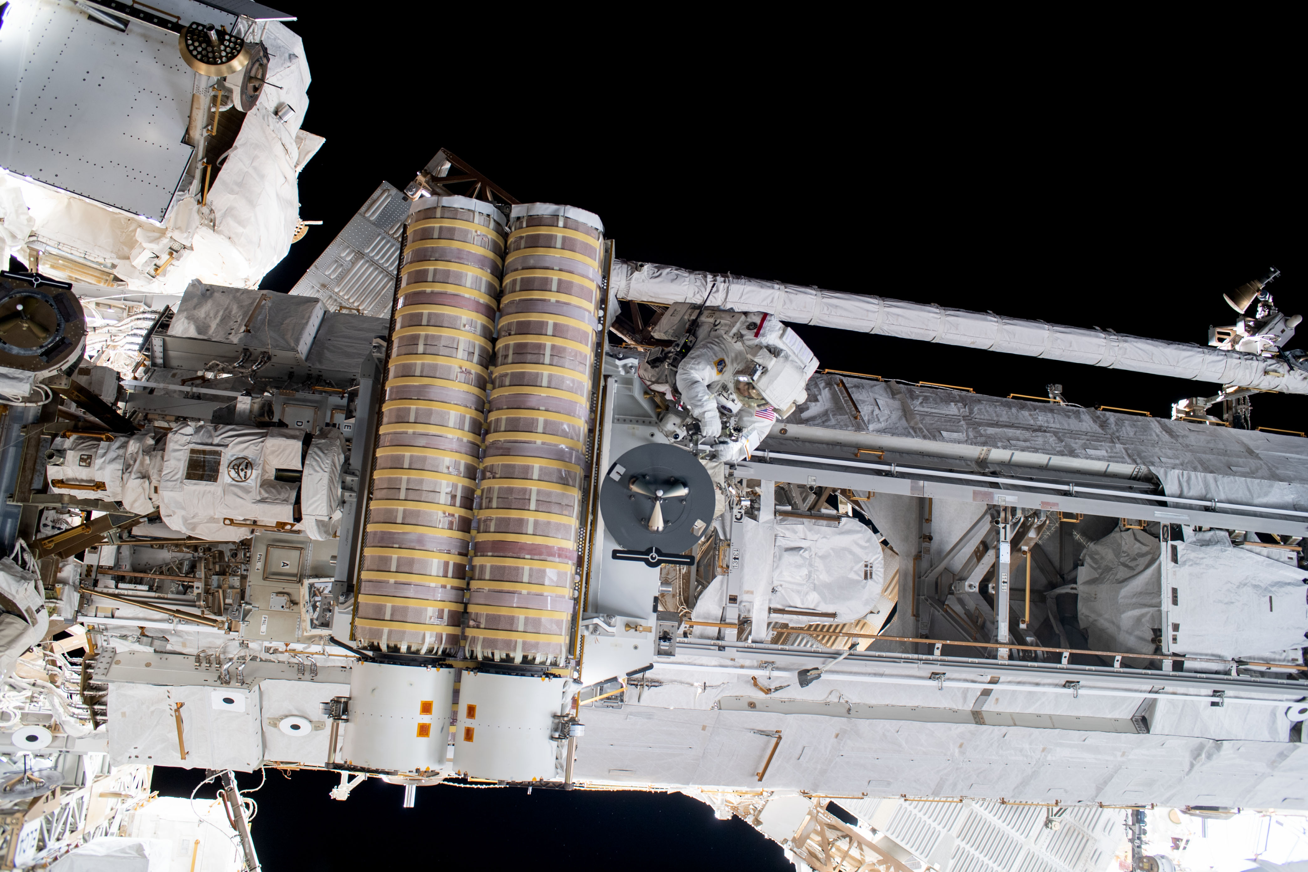 NASA astronaut and Expedition 69 Flight Engineer Stephen Bowen (center) is pictured working to release a stowed roll-out solar array attached to the International Space Station's starboard truss structure during a six-hour and three-minute spacewalk.