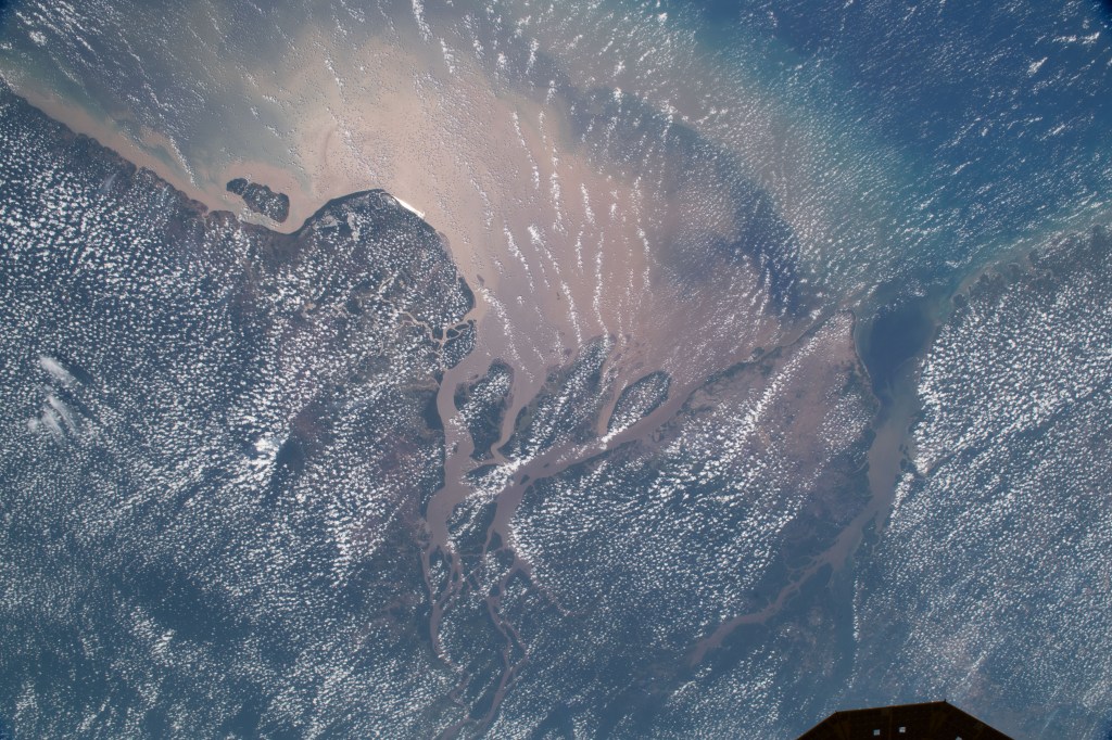 The Amazon river meets the Atlantic Ocean as an array of scattered clouds linger above Ampa, a state in Northern Brazil. Sediment that pours from the river gives off the milky brown color of the waters. The International Space Station orbited roughly 260 miles above as this image was taken.