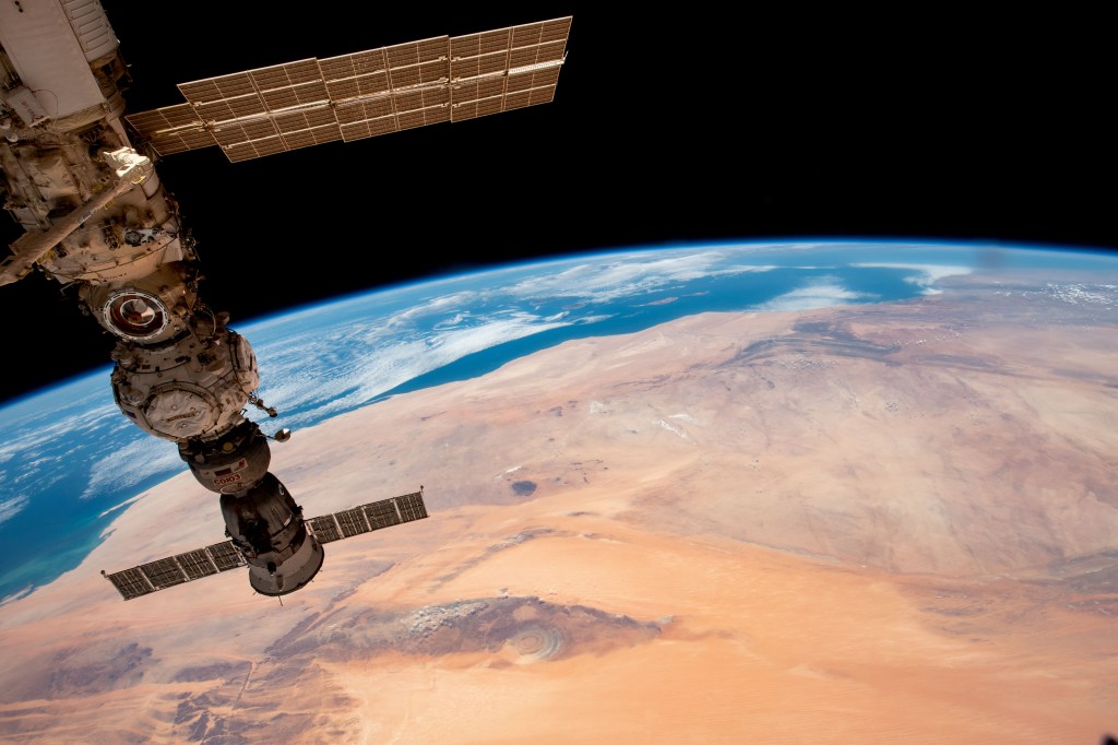 The Richat Structure, also known as the "Eye of the Sahara," an eroded geological dome in the nation of Mauritania, is pictured from the International Space Station as it orbited 259 miles above the African continent. At left, from top to bottom, are the Nauka multipurpose laboratory module's forward port, the Prichal docking module, and the Soyuz MS-23 crew ship.