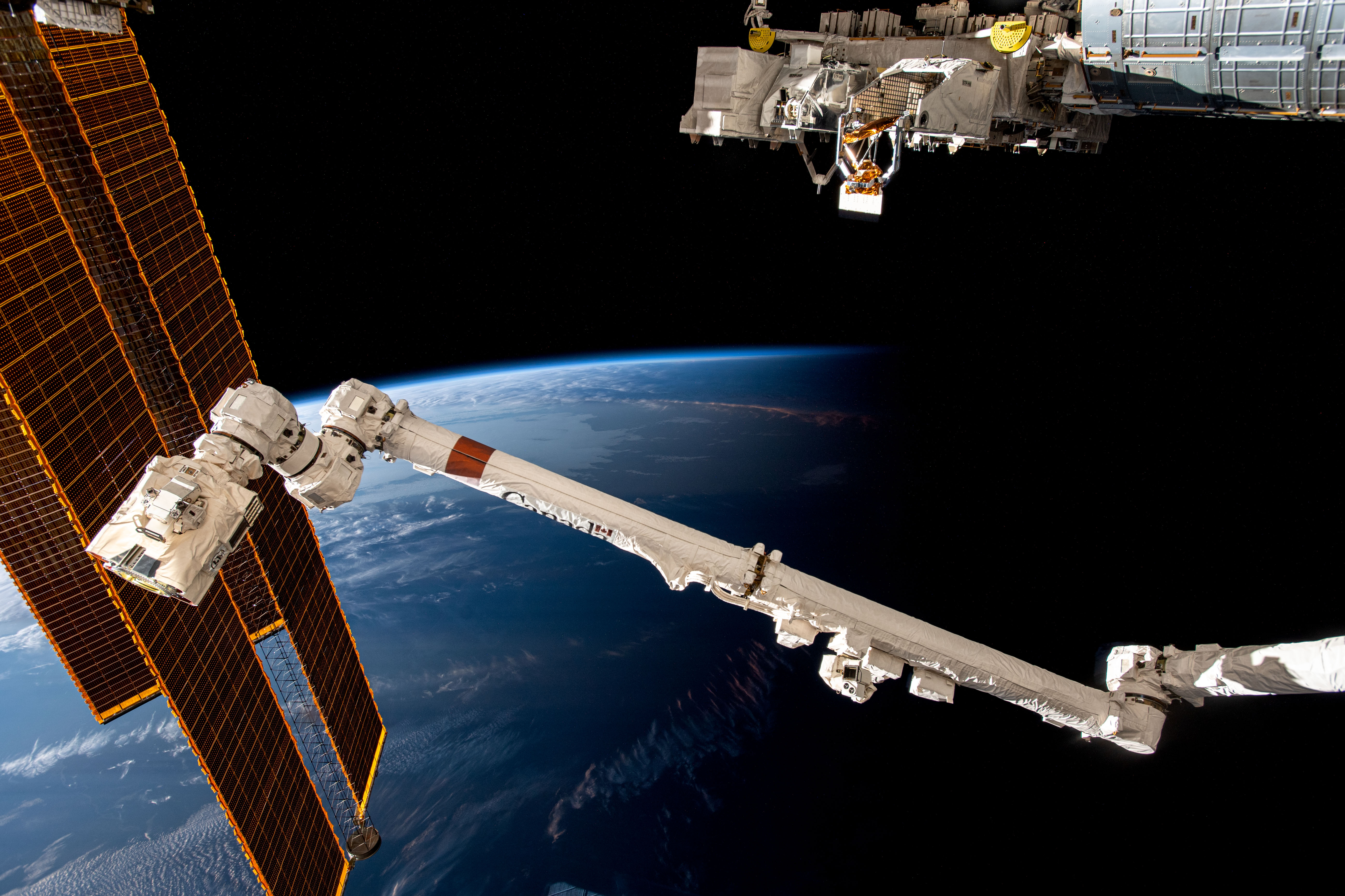 The International Space Station soars 266 miles above the coast of Argentina near the Rio de la Plata as it flies into an orbital sunset. In the foreground from left are, the station's main solar arrays, the Canadarm2 robotic arm, and the Kibo laboratory module's external research platform.