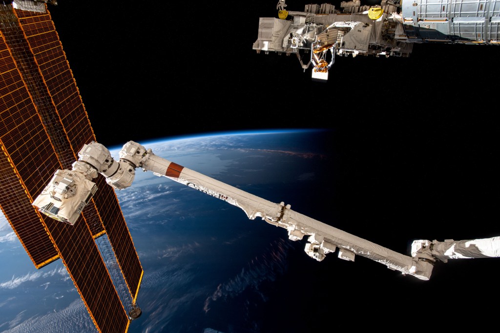 The International Space Station soars 266 miles above the coast of Argentina near the Rio de la Plata as it flies into an orbital sunset. In the foreground from left are, the station's main solar arrays, the Canadarm2 robotic arm, and the Kibo laboratory module's external research platform.