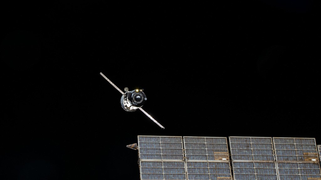 The ISS Progress 79 resupply ship from Roscosmos is pictured departing the vicinity of the International Space Station after undocking from the Zvezda service module's rear port. In the foreground, one of two solar arrays attached to Zvezda is pictured.