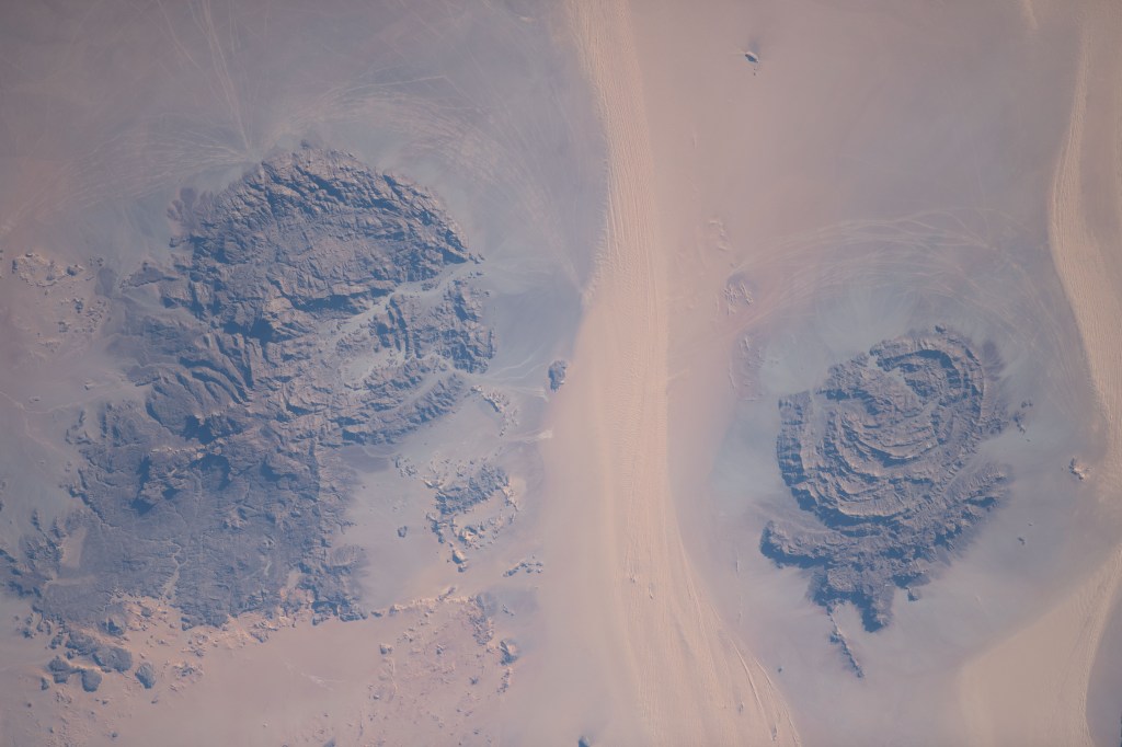 Located in the Libyan Desert along the country's southeastern border with Sudan and Egypt are the Jebel Uweinat (left) and the Jabal Arkenu (right) mountains pictured from the International Space Station as it orbited 258 miles above.