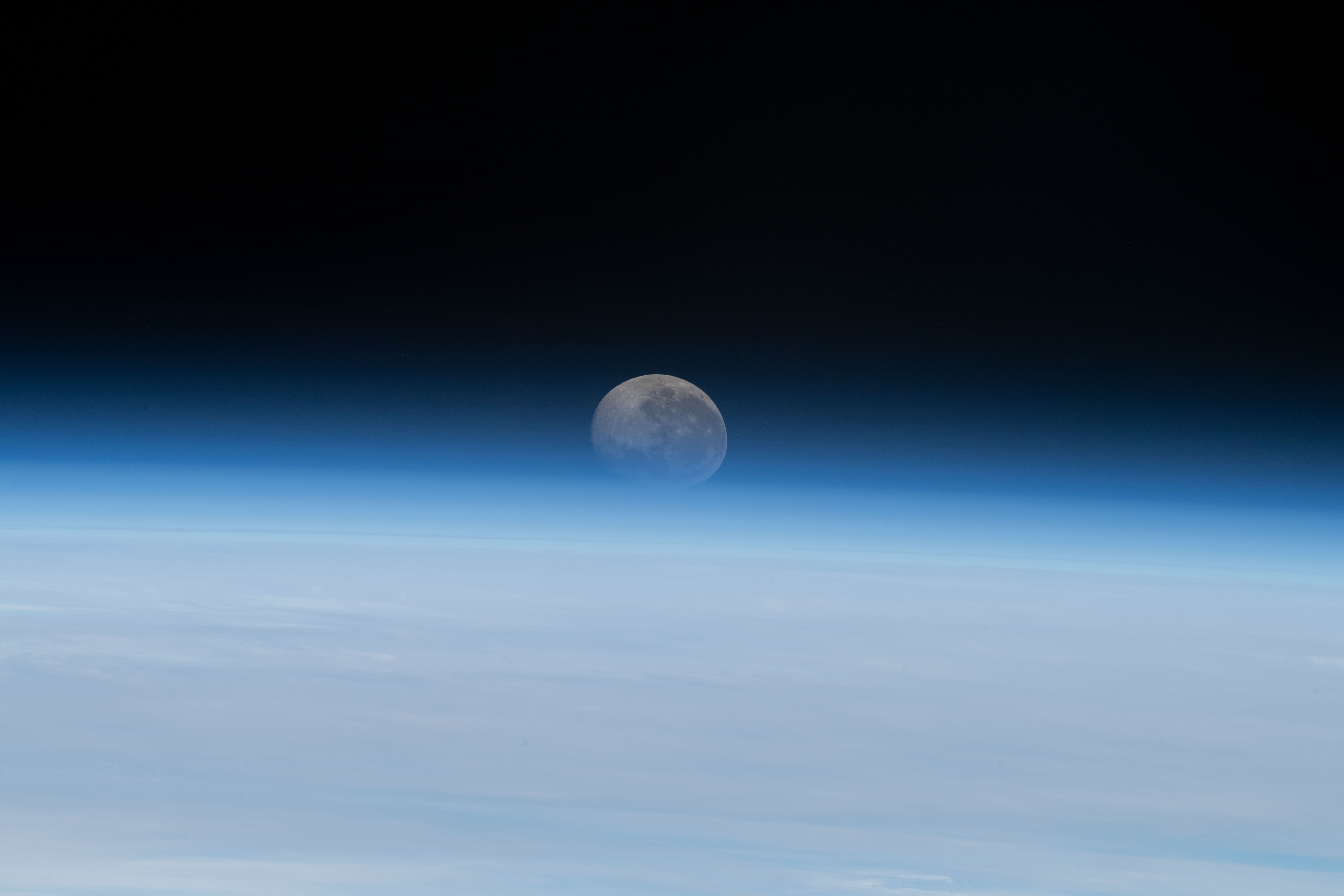 The Moon begins setting below Earth's horizon the atmosphere refracting, or bending, its light making it appear flatter in this photograph taken from the International Space Station as it orbited 262 miles above the Atlantic Ocean off the coast of Namibia.