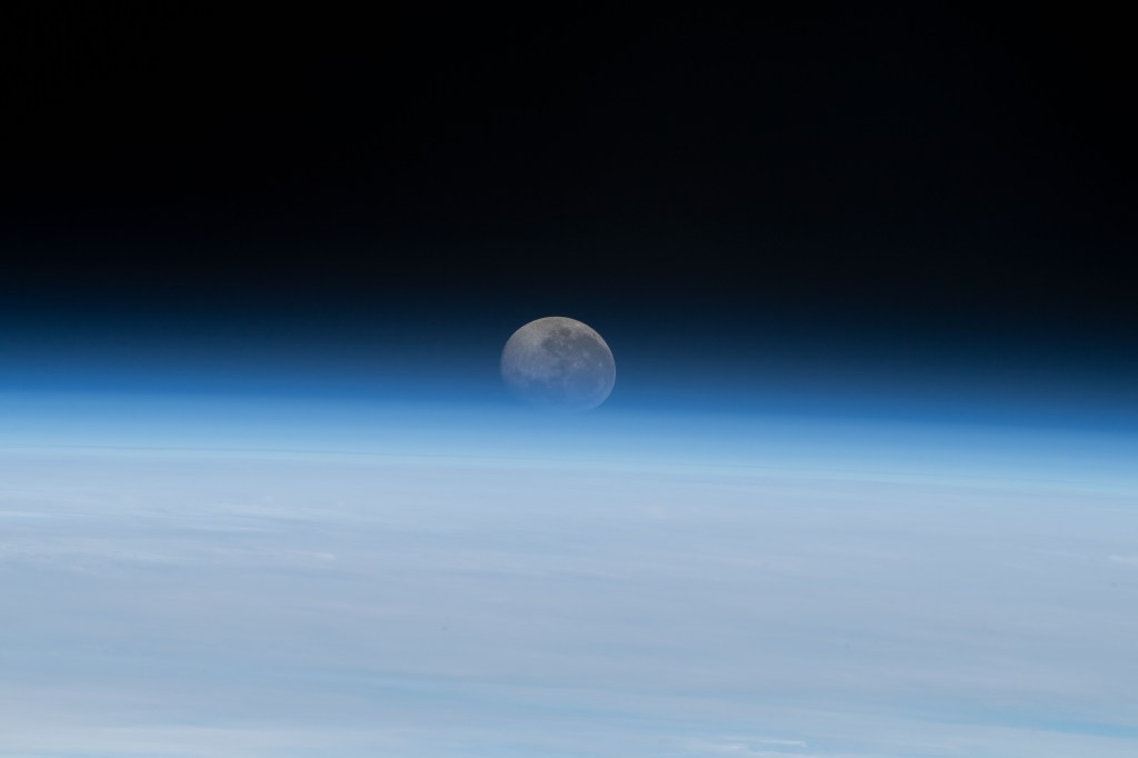 The Moon begins setting below Earth's horizon the atmosphere refracting, or bending, its light making it appear flatter in this photograph taken from the International Space Station as it orbited 262 miles above the Atlantic Ocean off the coast of Namibia.