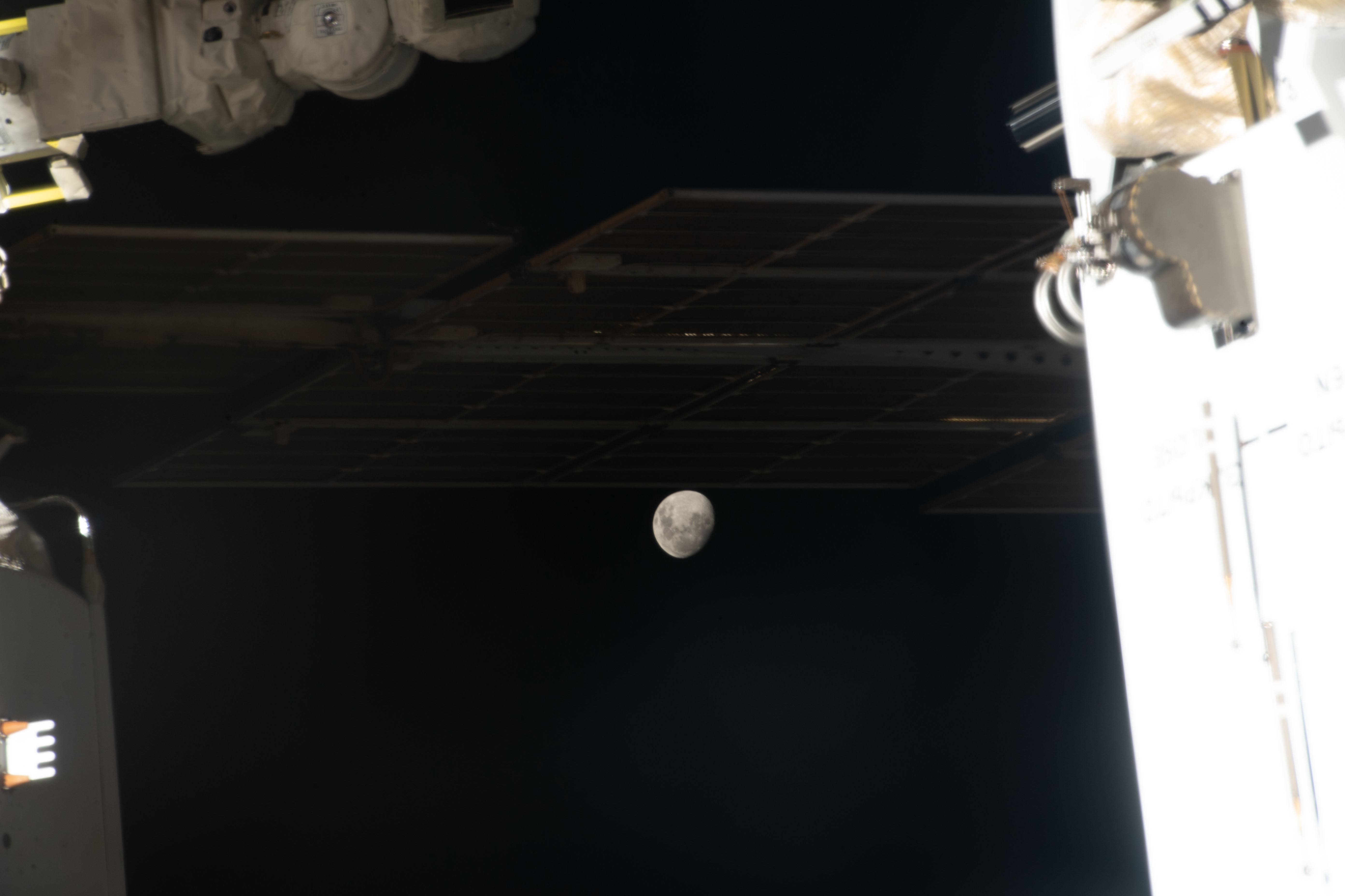 The Moon, with Earth's shadow draping across it during a lunar eclipse, is pictured in a gap in between International Space Station components.