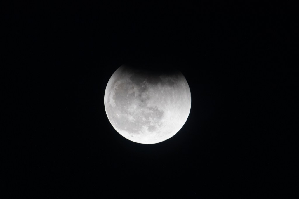 The Moon, with Earth's shadow draping across it during a lunar eclipse, is pictured from the International Space Station.