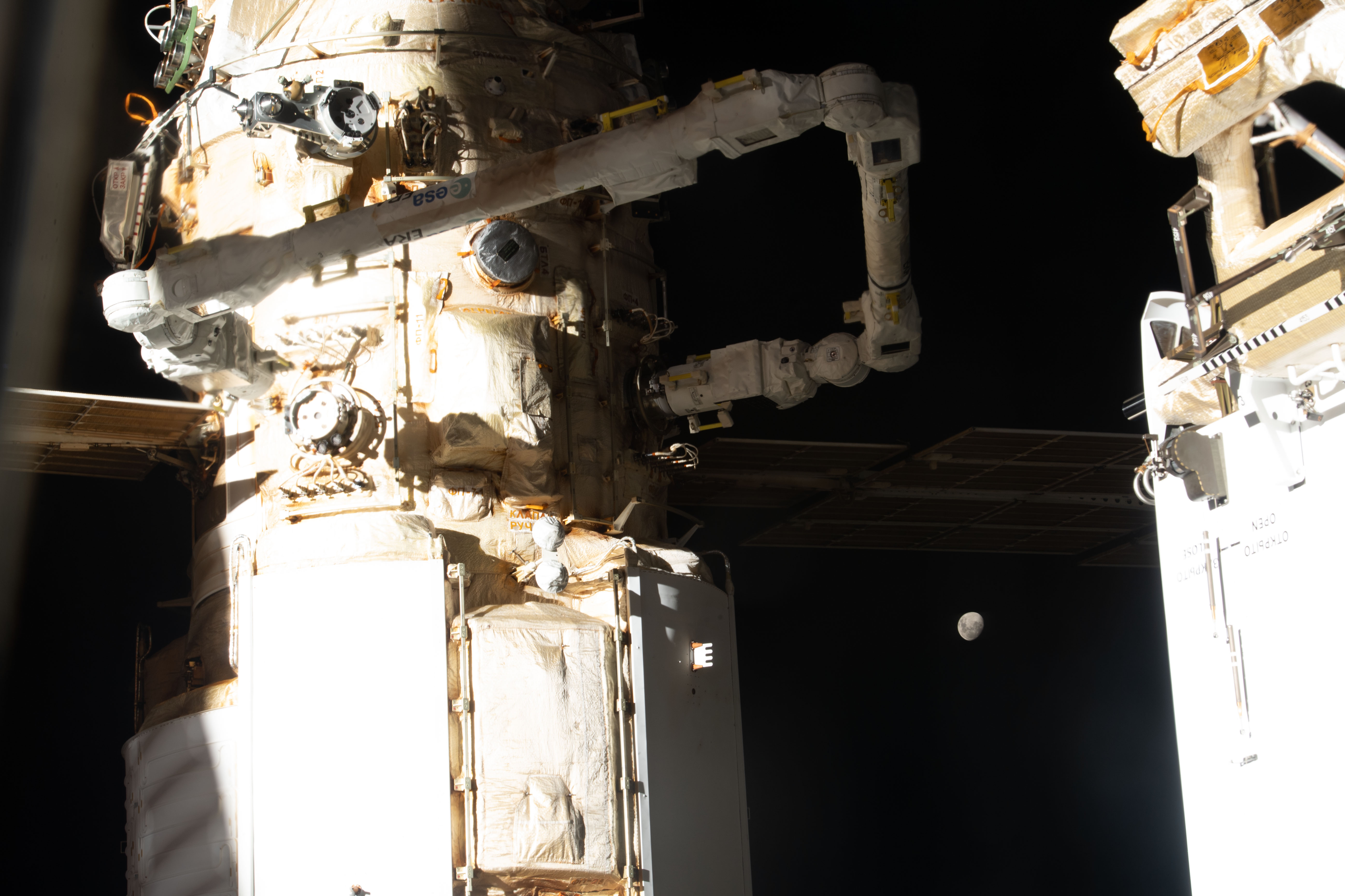 The Moon, with Earth's shadow draping across it during a lunar eclipse, is pictured in between the International Space Station's Nauka multipurpose laboratory module and the Rassvet module. Attached to Nauka, is the new European robotic arm that is continuing checkouts and mobility tests.