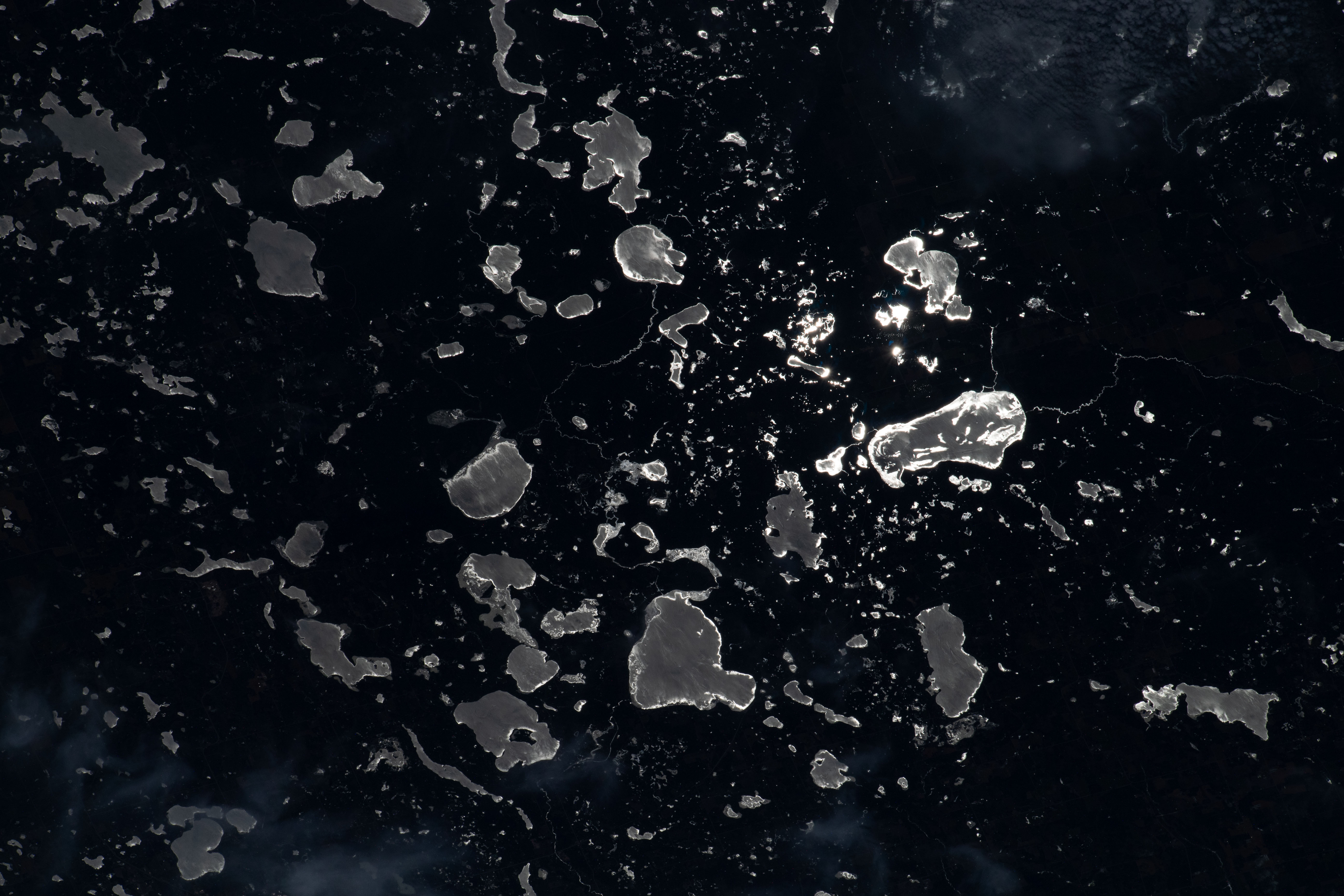 The Moon's glint beams off lakes on the U.S.-Canadian border, between the state of Minnesota and the province of Ontario, in this nighttime photograph from the International Space Station as it orbited 260 miles above North America.