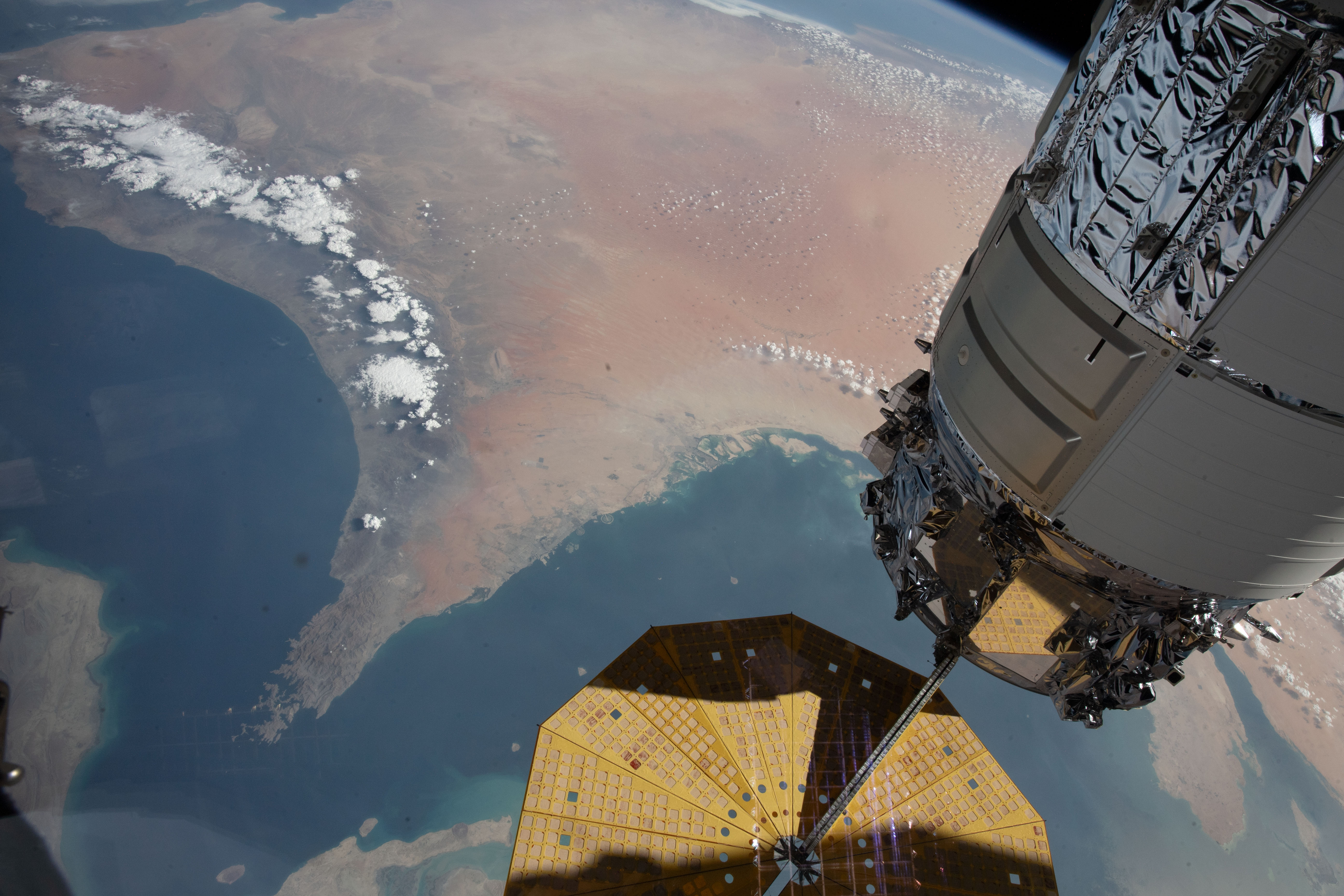 The Strait of Hormuz (bottom left) connects the Gulf of Oman with the Persian Gulf in this photograph from the International Space Station as it orbited 262 miles above southwestern Iran. In the right foreground, is the Northrop Grumman Cygnus space freighter and one of its cymbal-shaped UltraFlex solar arrays.