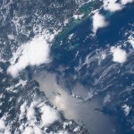 The Sun casts a glass-like reflection on the Atlantic Ocean off the coast of Honduras. Near the top of the image, groups of teal waters off the coast of Belize peek through the clouds as the International Space Station soared nearly 260 miles above.
