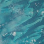 Small scatters of clouds lightly hang over the dark blue and turquoise waters of the Bahamas as the International Space Station soared 262 miles above.