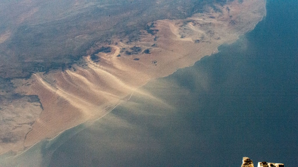 Windblown sand drifts across the Namib desert on the African continent and into the Atlantic Ocean in this photograph from the International Space Station as it orbited 266 miles above.