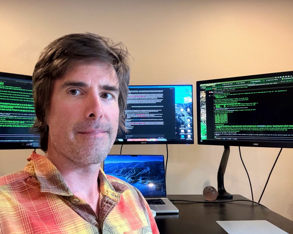 portrait of a man in front of some computer monitors
