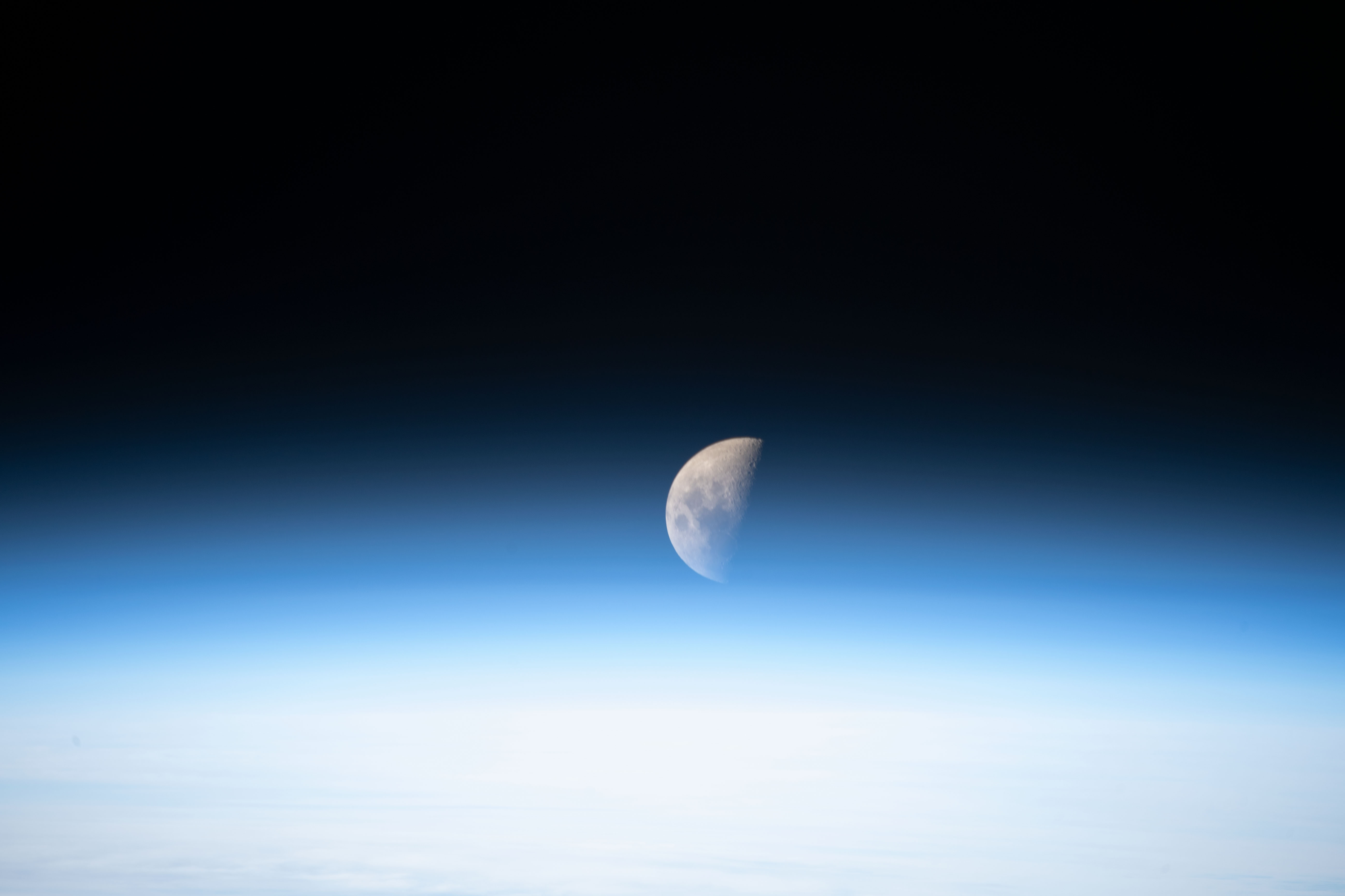 A first quarter Moon is pictured from the International Space Station just above the Earth's limb.