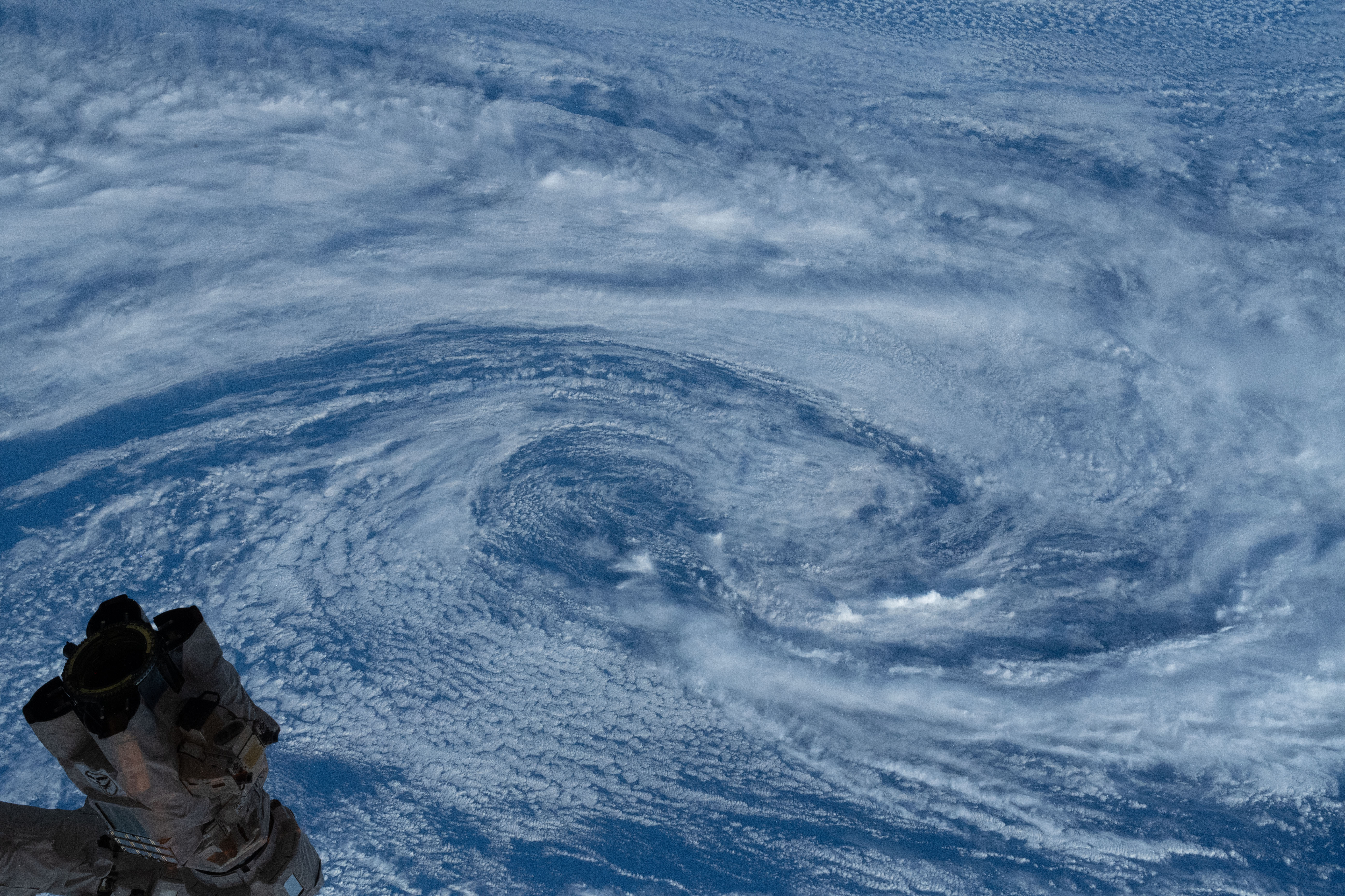The International Space Station's robotic arm, the 57.7-foot-long Canadarm2, crosses the frame with a typhoon pictured below in the South Pacific Ocean.