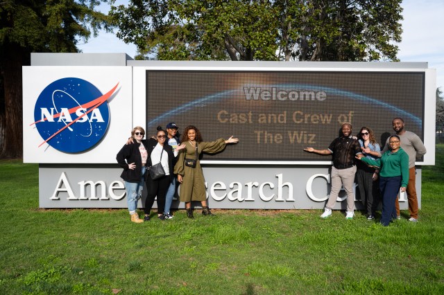 The cast and crew of The Wiz in front of the Ames Research Center's sign.