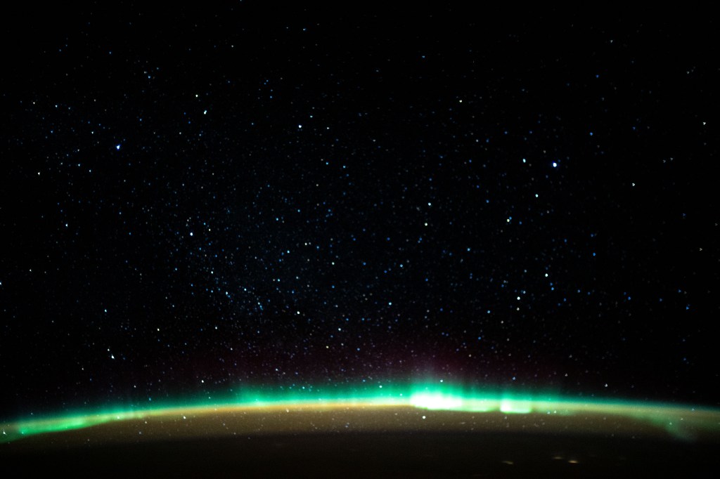 An aurora blankets the Earth beneath a celestial night sky as the International Space Station orbited 261 miles above the Atlantic Ocean off the coast of North America.