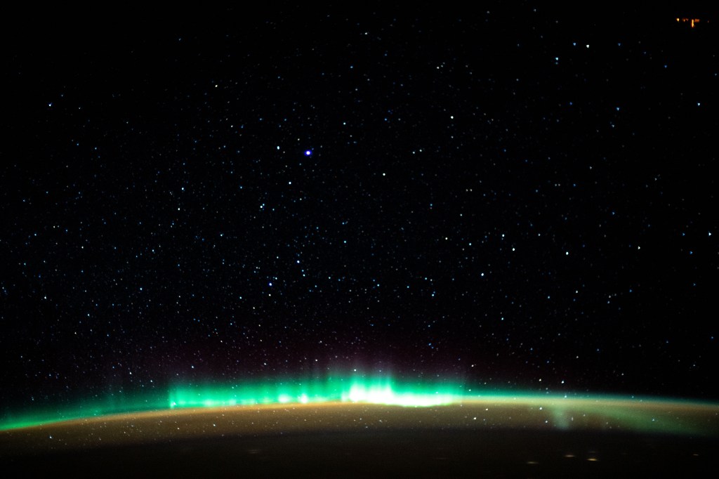 An aurora blankets the Earth beneath a celestial night sky as the International Space Station orbited 261 miles above the Atlantic Ocean off the coast of North America.