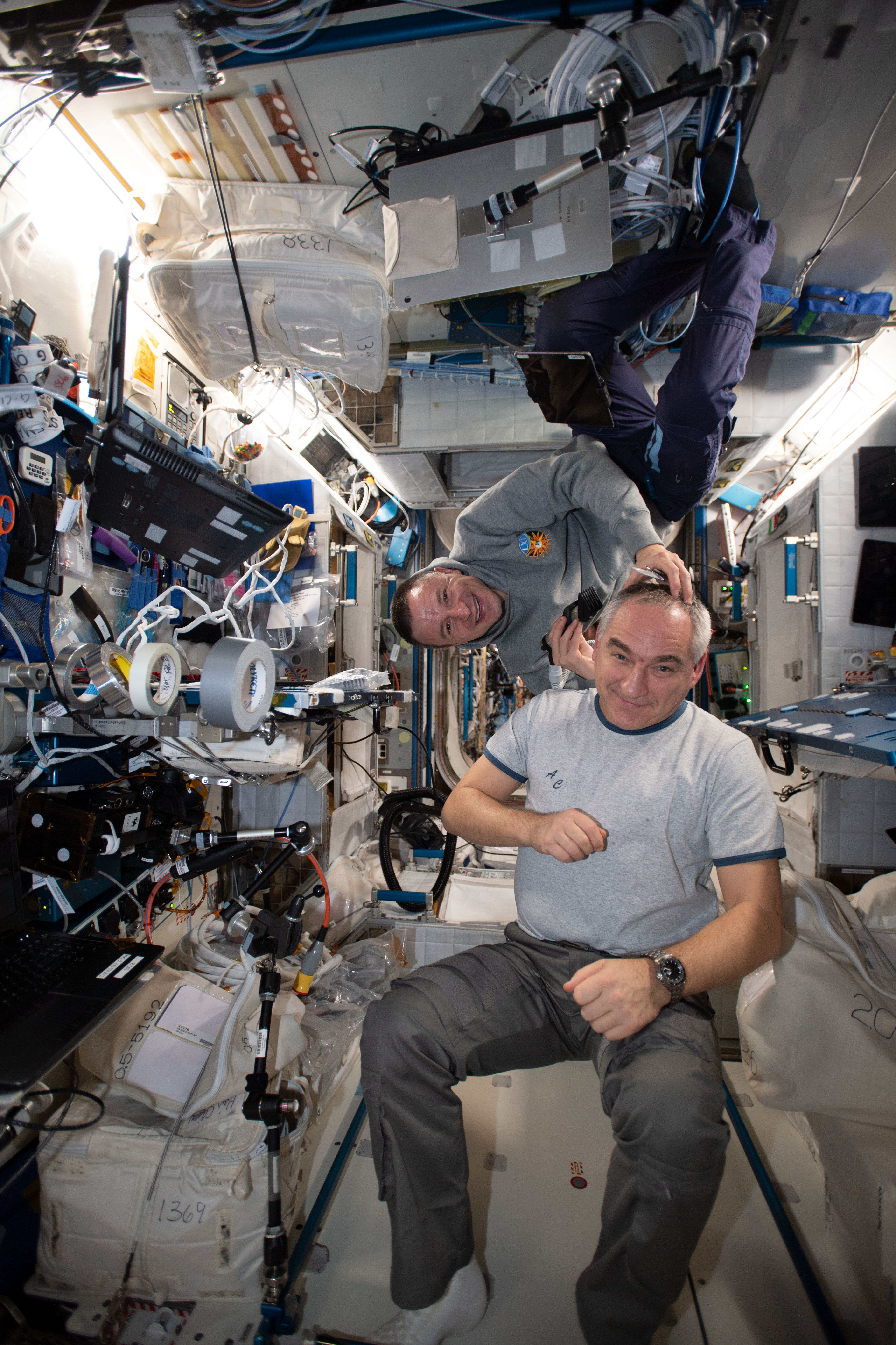 NASA astronaut Andrew Morgan (right) took a break from his engineering and science duties aboard the International Space Station to trim the hair of Roscosmos cosmonaut Alexander Skvortsov. A vacuum is attached to the clippers that draws the loose hair in to keep the cabin atmosphere clean.