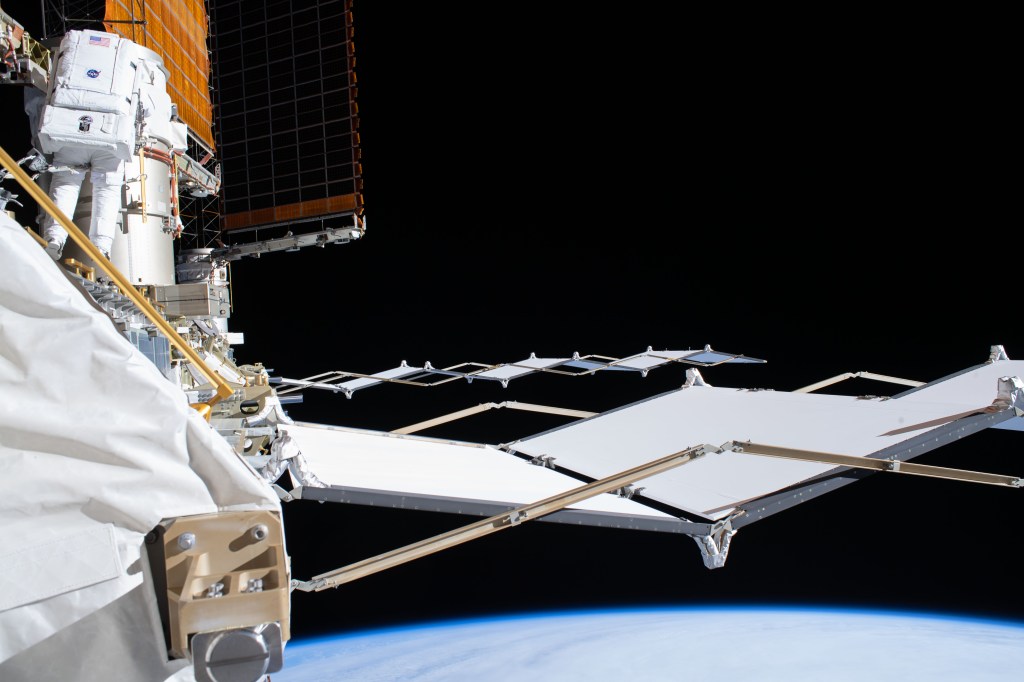 NASA astronaut and Expedition 63 Flight Engineer Bob Behnken (upper left) works during a six-hour and one-minute spacewalk to swap an aging nickel-hydrogen battery for a new lithium-ion battery on the International Space Station's Starboard-6 truss structure. Protruding horizontally from the truss are the Thermal Control System radiators that dispel heat generated by the orbiting lab's power systems.