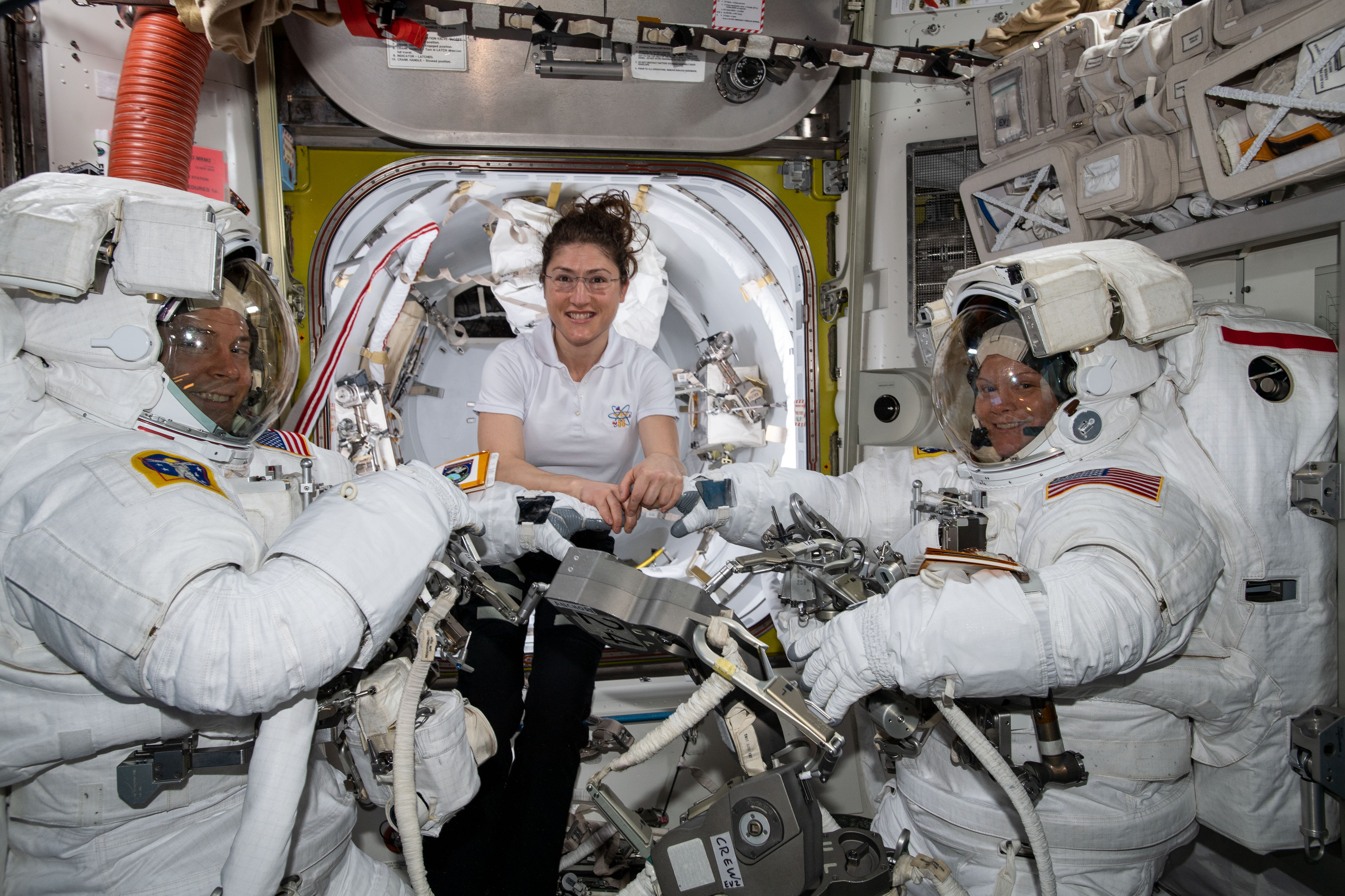 NASA astronaut Christina Koch (center) assists spacewalkers Nick Hague (left) and Anne McClain in their U.S. spacesuits shortly before they begin t...