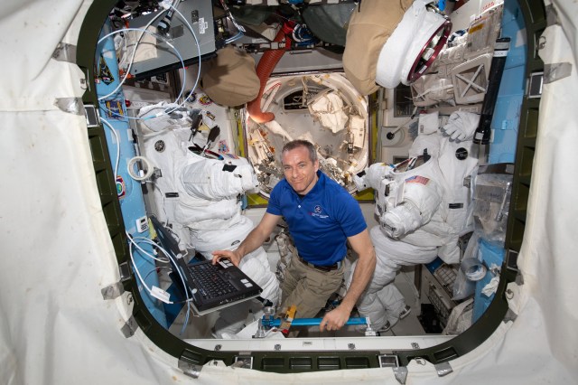 Astronaut David Saint-Jacques of the Canadian Space Agency works on a pair of U.S. spacesuits inside the Quest airlock ahead of a trio of spacewalks to upgrade power systems on the International Space Station.