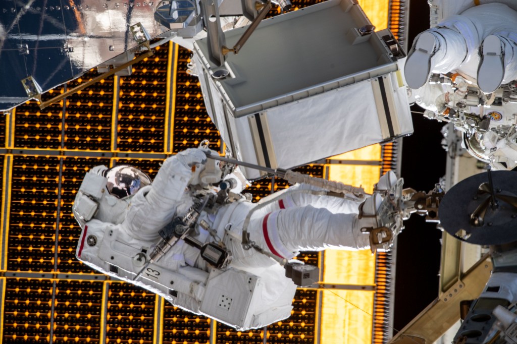 NASA astronaut Jessica Meir is attached to an articulating portable foot restraint during a spacewalk with NASA astronaut Christina Koch (upper right) to finalize upgrading power systems on the International Space Station's Port-6 truss structure.