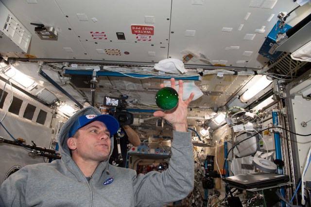 iss068e051621 (Feb. 12, 2023) --- NASA astronaut and Expedition 68 Flight Engineer Josh Cassada plays with a sphere of water flying in microgravity that has been dyed with green food coloring and is bubbling due to an antacid that was placed inside.