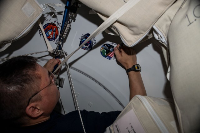 iss068e012479 (Oct. 5, 2022) --- NASA astronaut and Expedition 68 Flight Engineer Kjell Lindgren signs his name around the OFT-2 (Orbital Flight Test-2) mission insignia sticker affixed to the Harmony module's vestibule. Lindgren was aboard the International Space Station when Boeing's CST-100 Starliner spacecraft docked to Harmony's forward port on May 19, 2022, for a six-day uncrewed test mission.