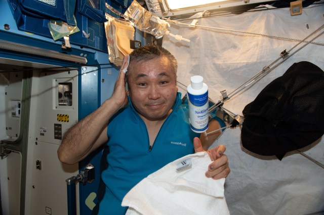 iss068e046501 (Feb. 5, 2023) --- Expedition 68 Flight Engineer Koichi Wakata of the Japan Aerospace Exploration Agency (JAXA) demonstrates washing his hair on the International Space Station using rinseless shampoo and without shower facilities. Showers are not possible in space due to limited water supplies and the effects of microgravity.