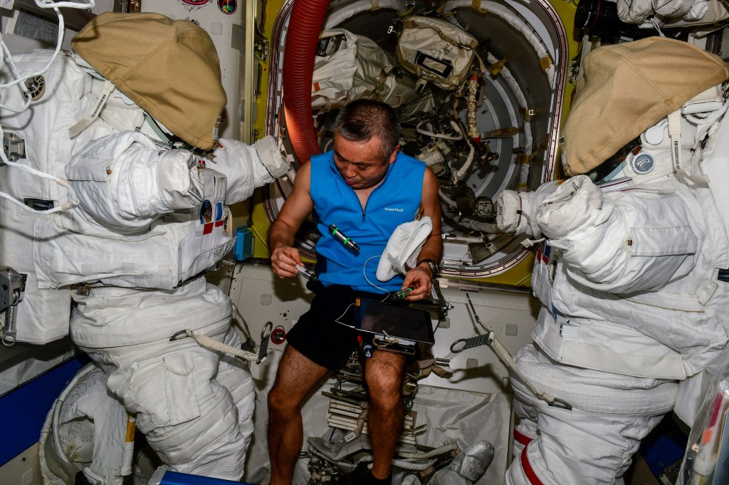 iss068e041023 (Jan. 19, 2023) --- Expedition 68 Flight Engineer Koichi Wakata of the Japan Aerospace Exploration Agency (JAXA) is photographed in between a pair of Extravehicular Mobility Units, or spacesuits, inside the International Space Station's Quest airlock. Credit: Roscosmos