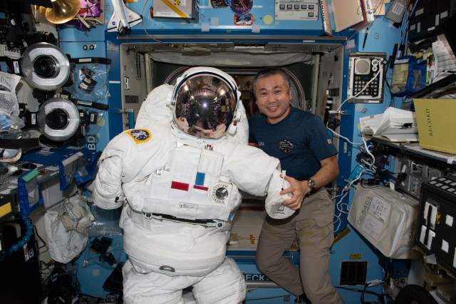 iss068e033710 (Dec. 28, 2022) --- Expedition 68 Flight Engineer Koichi Wakata of the Japan Aerospace Exploration Agency (JAXA) poses with an Extravehicular Mobility Unit (EMU), also known as a spacesuit, aboard the International Space Station.