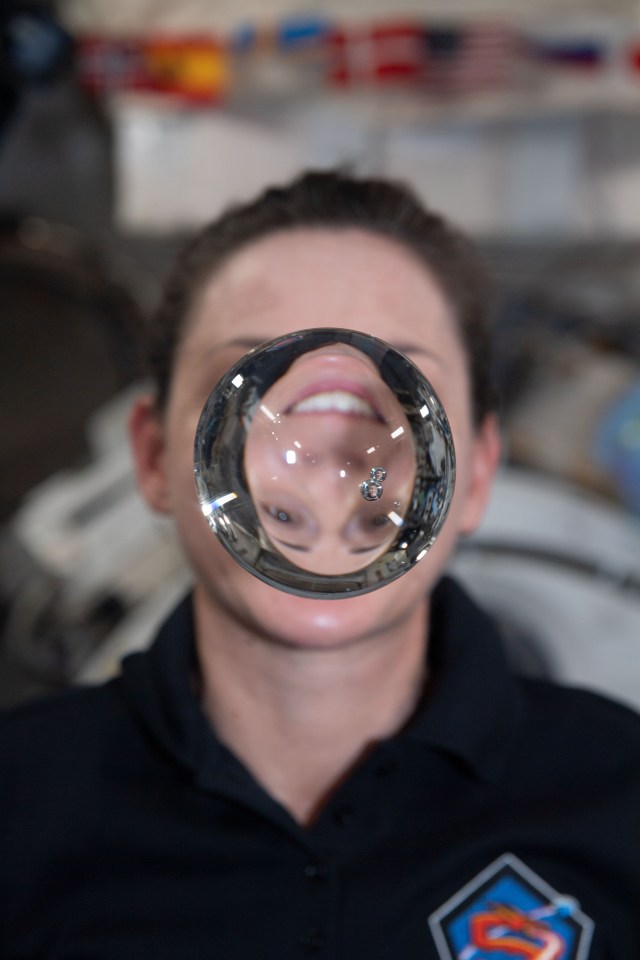 iss068e051522 (Feb. 12, 2023) --- NASA astronaut and Expedition 68 Flight Engineer Nicole Mann's image is refracted through a sphere of water flying weightlessly in microgravity.