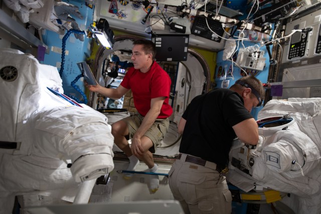 (From left) Expedition 63 Commander Chris Cassidy and Flight Engineer Bob Behnken work on U.S. spacesuit maintenance inside the International Space Station's Quest airlock.