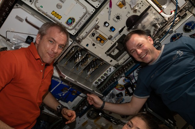 Astronauts David Saint-Jacques and Nick Hague eagerly await pizzas being cooked aboard the International Space Station's galley.