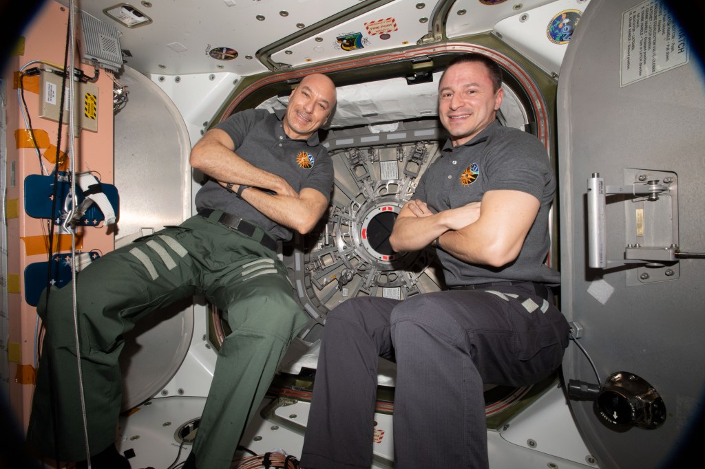 Astronauts (from left) Luca Parmitano of ESA (European Space Agency) and Andrew Morgan of NASA pose for a portrait in front the hatch that opens to the Cygnus space freighter from Northrop Grumman.