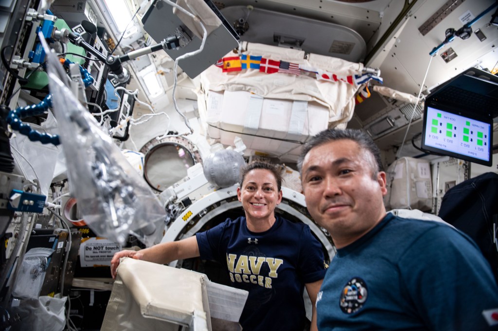 iss068e028226 (Dec. 9, 2022) --- Expedition 68 Flight Engineers Nicole Mann of NASA and Koichi Wakata of the Japan Aerospace Exploration Agency (JAXA) remove a small satellite deployer from the Multi-Purpose Experiment Platform inside the Kibo laboratory module's airlock.