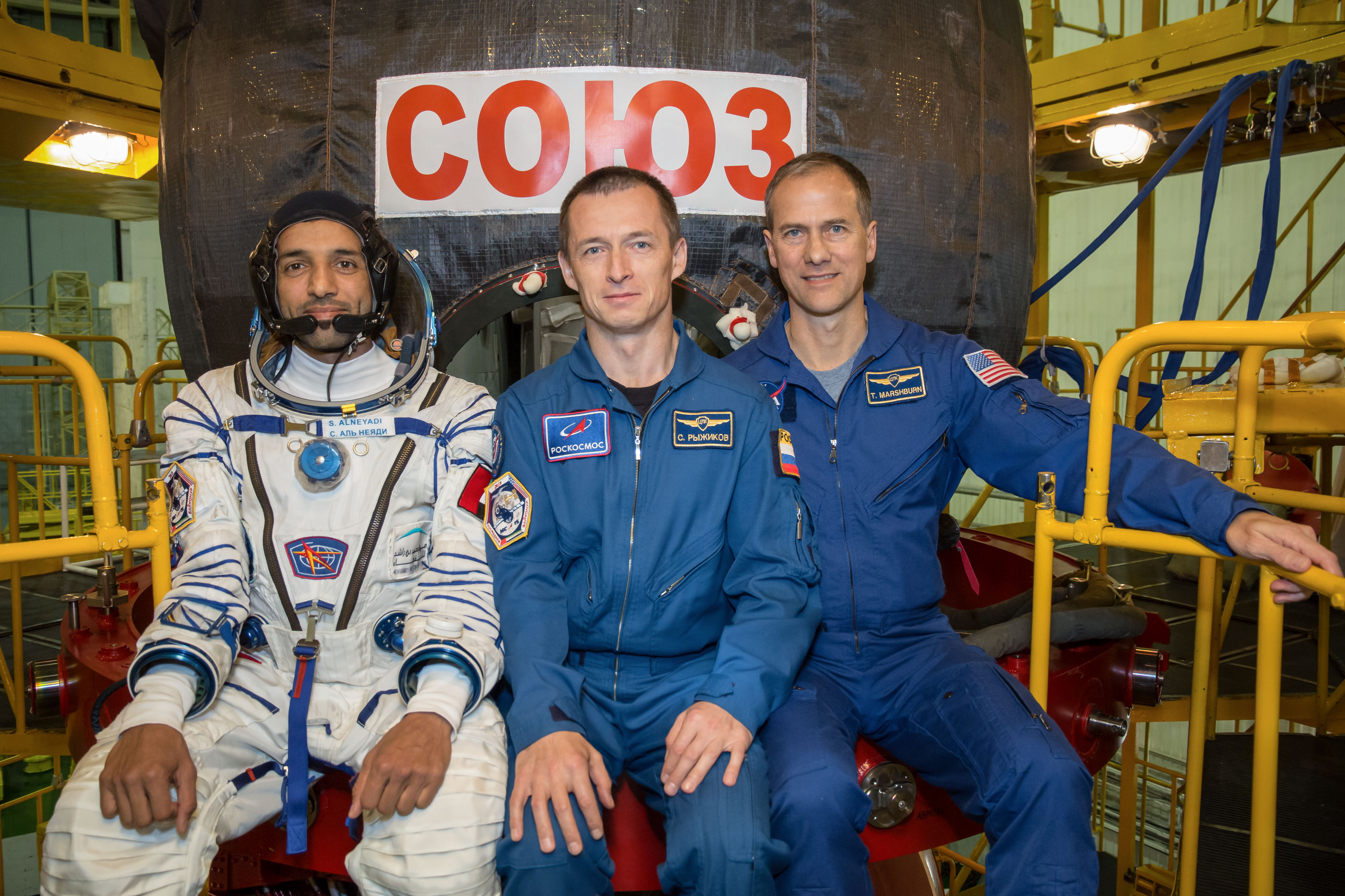 In the Integration Building at the Baikonur Cosmodrome in Kazakhstan, backup spaceflight participant Sultan Al-Neyadi of the United Arab Emirates (left) and backup Expedition 61 crewmates Sergey Ryzhikov of Roscosmos (center) and Tom Marshburn of NASA (right) pose for pictures Sept. 11 in front of the Soyuz MS-15 spacecraft. They are the backups to the prime crew, spaceflight participant Hazzaa Ali Almansoori of the United Arab Emirates and Expedition 61 crewmembers Oleg Skripochka of Roscosmos and Jessica Meir of NASA, who will launch Sept. 25 on the Soyuz MS-15 spacecraft from the Baikonur Cosmodrome for a mission on the International Space Station.