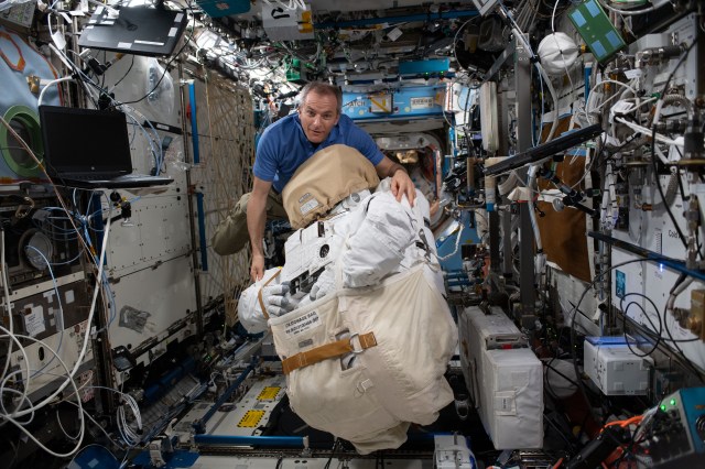 Canadian Space Agency astronaut David Saint-Jacques moves a U.S spacesuit inside the Destiny laboratory module.