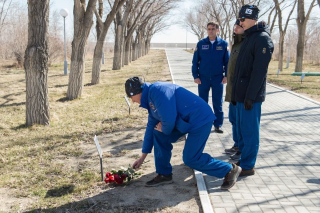 jsc2020e016869 (March 27, 2020) - Along the Walk of the Cosmonauts at the Cosmonaut Hotel crew quarters in Baikonur, Kazakhstan, Expedition 63 crewmember Chris Cassidy of NASA lays flowers March 27 at the site where the tree bearing the name of Yuri Gagarin, the first human to fly in space, is planted. March 27, 2020 marked the 52nd anniversary of Gagarin’s death at the age of 34. Looking on are cosmonaut Yuri Malenchenko, the Deputy Director of the Gagarin Cosmonaut Training Center, and Cassidy’s crewmates, Ivan Vagner and Anatoly Ivanishin of Roscosmos. Cassidy, Vagner and Ivanishin will launch April 9 on the Soyuz MS-16 spacecraft from the Baikonur Cosmodrome in Kazakhstan for a six-and-a-half month mission on the International Space Station.