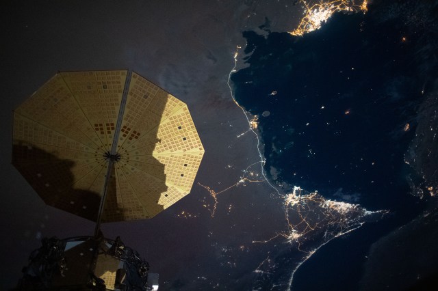 This nighttime image from the International Space Station shows the Persian Gulf city of Doha, Qatar (top right) and the United Arab Emirates cities (bottom right) of Abu Dhabi, Dubai and Ali Ain. In the foreground, is one of the cymbal-shaped UltraFLex solar arrays that powers the Cygnus space freighter from Northrop Grumman.