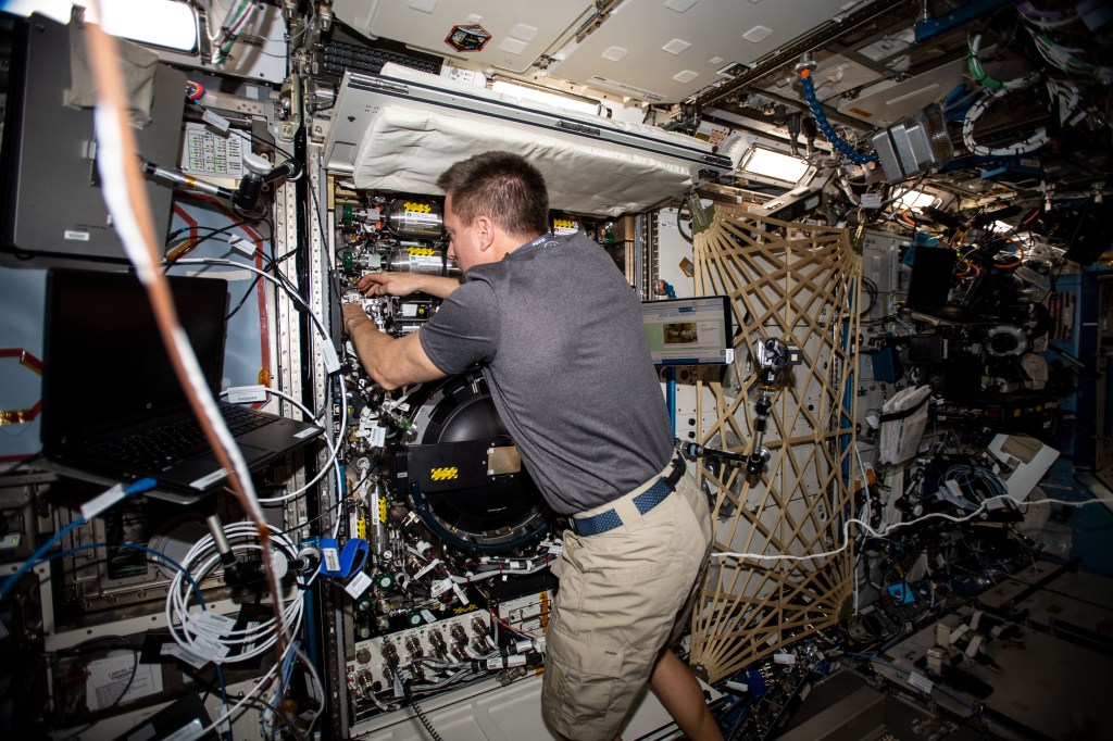 NASA astronaut and Expedition 63 Commander Chris Cassidy works in the Combustion Integrated Rack, connecting water umbilicals and checking for leaks in the research device that enables safe fuel, flame and soot studies in microgravity.