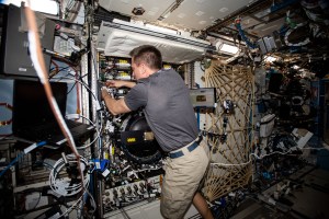NASA astronaut and Expedition 63 Commander Chris Cassidy works in the Combustion Integrated Rack, connecting water umbilicals and checking for leaks in the research device that enables safe fuel, flame and soot studies in microgravity.