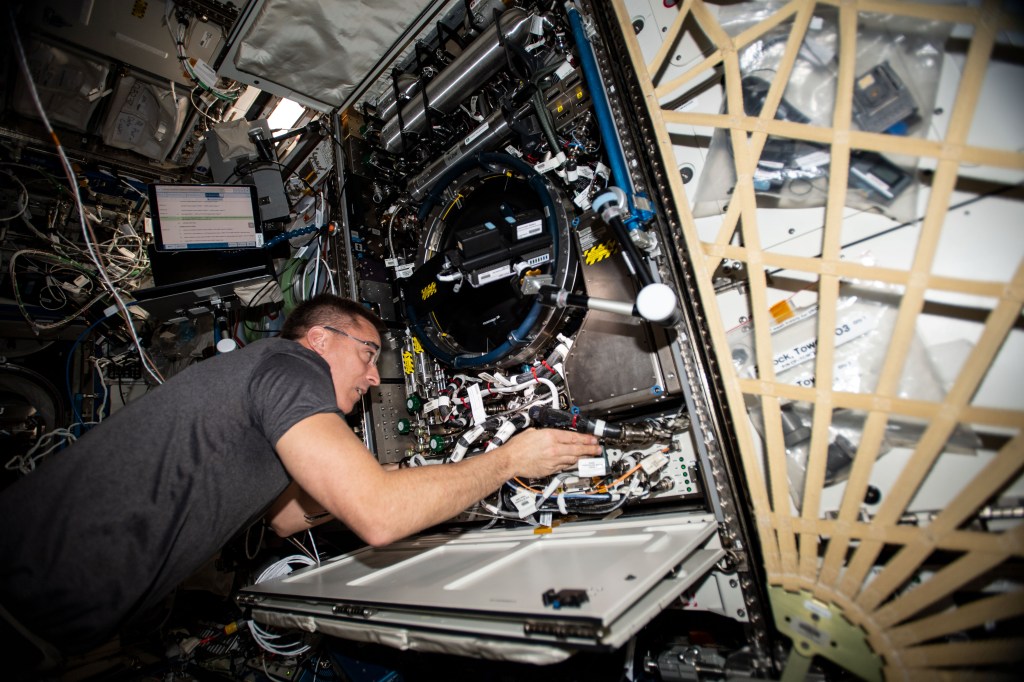NASA astronaut and Expedition 63 Commander Chris Cassidy works in the Combustion Integrated Rack, connecting water umbilicals and checking for leaks in the research device that enables safe fuel, flame and soot studies in microgravity.